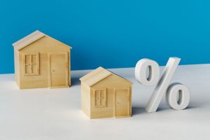 Zwei hölzerne Hausmodelle und ein Prozentzeichen (Foto: freepik, Shoaib Attock) - Immobilien: Tief am Finanzierungsmarkt und Wohnindex sackt ab
