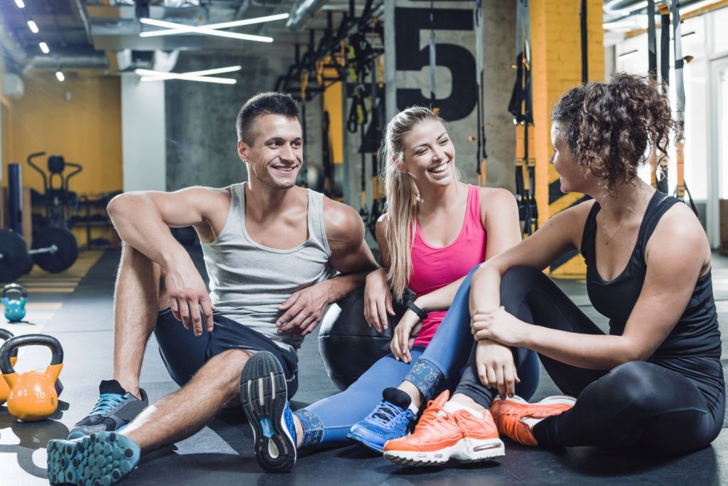 Drei junge Sportler sitzen in einer Trainingspause in einem Gym (Foto: Freepik) - FIBO 2024 Köln: Messe-Highlights im Überblick – Fitness Wellness Gesundheit