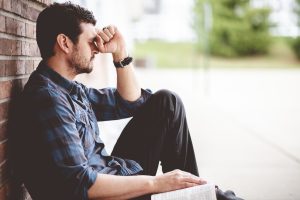 Einsame depressive Person sitzt vor einer Ziegelmauer - In Haushalten mit Doppelverdienern sind Depressionen seltener