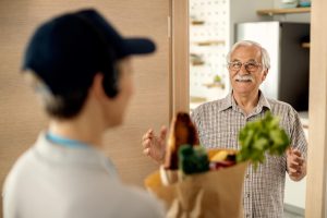Mann empfängt Lebensmittel an der Haustür - Aldi plant Online-Shop für Lebensmittel