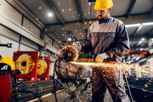 Metallarbeiter in einer Fabrik bearbeitet ein Werkstück mit einer Schleifmaschine (Foto: freepik, dusanpetkovic)