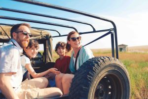 Familie auf der Ladefläche eines Jeeps in einer Graslandschaft (Foto: TUI AG) - Urlaub 2023: TUI rät früh zu buchen – Trends bei Reisezielen
