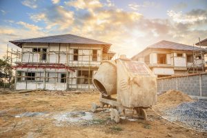 Zwei Einfamilienhäuser im Rohbau, davor eine Betonmischmaschine (Foto: freepik, kwangmoop) - Baukrise 2023: Genehmigungen im Keller – Branche in Not