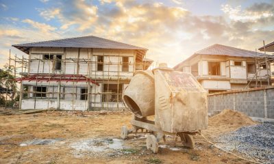 Zwei Einfamilienhäuser im Rohbau, davor eine Betonmischmaschine (Foto: freepik, kwangmoop)