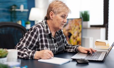 Ältere Frau arbeitet am Schreibtisch mit Laptop