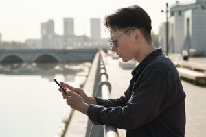 Chinese mit Smartphone an Flussufer (Foto: freepik, pressmaster) - Ärger mit Apple: Datentransfer manipuliert und Nutzer ausspioniert
