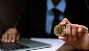 Geschäftsmann am Laptop mit Bitcoin-Münze (Foto: freepik, jadethaicatwalk) - Trotz FTX: Institutionelle Anleger halten Krypto die Treue