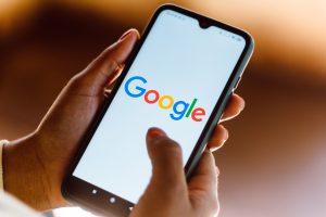 Hände halten ein Smartphone mit der Google-Suchseite (Foto: freepik, rafapress) - Google Anzeigen: Kampf gegen Fake News und Betrug - 5 Milliarden Löschungen
