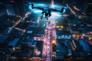 Drohne mit erleuchteten Rotoren über einer Stadt (Foto: freepik, vecstock) - Neuartige Lasertechnik: Lichtenergie treibt Motoren von Drohnen an