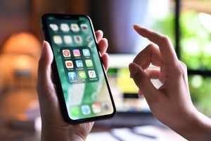 Frau hält ein Smartphone mit App-Symbolen auf dem Bildschirm - 2022 zahlen Deutsche über 3 Milliarden Euro für Apps
