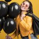 Junge Frau mit schwarzen Luftballons wirbt für Black Friday (Foto: Freepik)