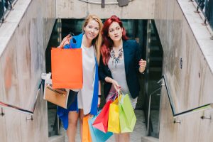 Zwei Frauen beim Shopping mit Einkauftaschen auf einer Treppe (Foto: freepik, freepik) - Black Friday lockt mit Rabatten und Aktionen bei Amazon und Co.
