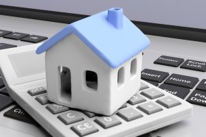Modellhaus auf Taschenrechner und Computer-Tastatur (Foto: freepik, Rawf8.com) - Baufinanzierung online: neuer Self-Service für Immobilienkredite