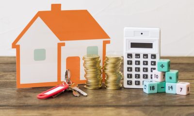 Arrangement mit Münzen, Taschenrechner, Hausmodell und Schlüssel - Kredite für Immobilien (Foto: Freepik)