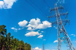 Hochspannungsleitung in Waldgebiet vor blauem Himmel (Foto: freepik, MrDm) - Blockchain bewahrt Stromnetze vor Blackout