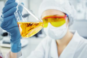 Junge Frau im Chemie-Labor, die ein Teströhrchen mit gelber Flüssigkeit hält - Start-ups haben zu wenig Kapital für Innovationen
