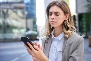 Junge Frau schaut skeptisch auf ihr Smartphone (Foto: freepik, benzoix) - Telefonwerbung: verbotene Anrufe rückläufig – unlautere Firmen melden