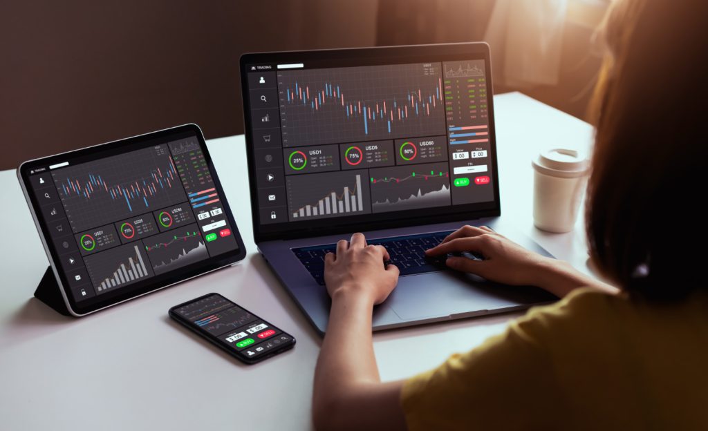 KI und Trading: Frau vor einem Laptop auf dem Charts von Aktienkursen abgebildet sind (Foto: freepik) - KI-gestütztes Trading: Maschinenlernen und Künstliche Intelligenz im Börsenhandel