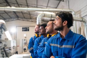 4 Arbeiter in blauen Overalls in einer Möbelfabrik (Foto: freepik, user6699736) US-Arbeitsmarkt aktuell – Jobzuwachs nach Fed-Zinsentscheid