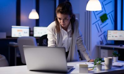 Eine Frau steht an einem Laptop in Büro, im Hintergrund Bildschirme (Foto: freepik, DCStudio)