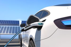 E-Auto beim Laden, dahinter Photovoltaik-Module (Foto: freepik, user6702303) - Rheinmetall: Wärmepumpe zweiter Streich – neues Klimasystem für E-Autos