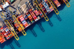 Luftaufnahme eines Container-Schiffs an einem Hafen-Terminal (Foto: freepik, tawatchai07) - Zeichen der Krise: Containerumschlag geht zurück