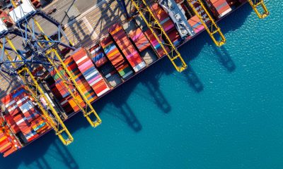 Luftaufnahme eines Container-Schiffs an einem Hafen-Terminal (Foto: freepik, tawatchai07)