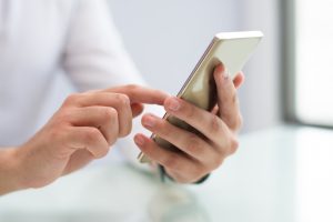 Nahaufnahme einer männlichen Hand, die ein Smartphone bedient - SMS steigert Überlebensrate bei Herzstillstand