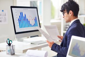 Manager vor einem Computer mit Diagrammen (Foto: freepik, pressfoto) - Hoffen auf Rezession light: Industrie pusht Einkäufer-Index