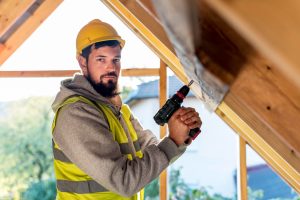 Handwerker arbeitet mit Bohrer am Dachstuhl eines Hauses (Foto: freepik) - Bauen sanieren modernisieren – immer mehr sparen mit Eigenleistung