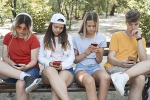 4 Teenager mit Handys auf einer Parkbank (Foto: freepik)