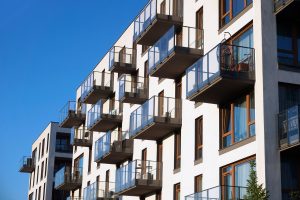 Mehrstöckiges modernes Wohnhaus mit Balkonen (Foto: freepik, pablographix) - Wohnungsmarkt: Heizgesetz Energiepreise Baukosten trüben Stimmung