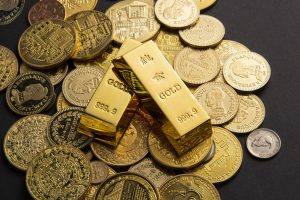 Goldmünzen und Goldbarren auf schwarzem Untergrund (Foto: freepik, wirestock) - Gold kaufen: Edelmetall im Portfolio – sinnvoll für Privatanleger?