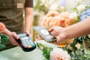 Kunde bezahlt per Handy in einem Geschäft (Foto: freepik, Lifestylememory) - Deutschland: Inflation sinkt in Zeitlupe – Branchentrends sehr unterschiedlich