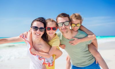 Mann, Frau und 2 Kinder mit Sonnenbrillen im Urlaub am Strand (Foto: freepik, travnikovstudio)