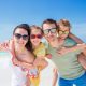 Mann, Frau und 2 Kinder mit Sonnenbrillen im Urlaub am Strand (Foto: freepik, travnikovstudio)