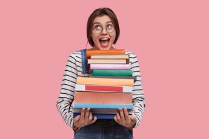 Junge Frau mit einem Stapel Bücher (Foto: Freepik, wayhomestudio) - Buchmesse Frankfurt 2023: Aktionen Bühnen Prominente – Highlights im Überblick
