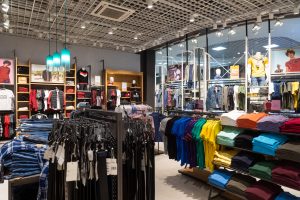 Verkaufsraum eines Bekleidungsgeschäfts mit Hemden und Jeans - Einzelhandel ächzt unter der Krise