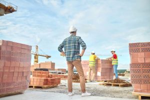 3 Bauarbeiter auf einer Haus-Baustelle (Foto: freepik, zinkevych) - Wohnungsmangel Deutschland: Bauaufträge abgesackt – Branche appelliert an Ampel