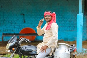 Junger Inder mit Smartphone auf Motorrad - Viele Inder bekommen Mini-Löhne trotz Wirtschaftsboom